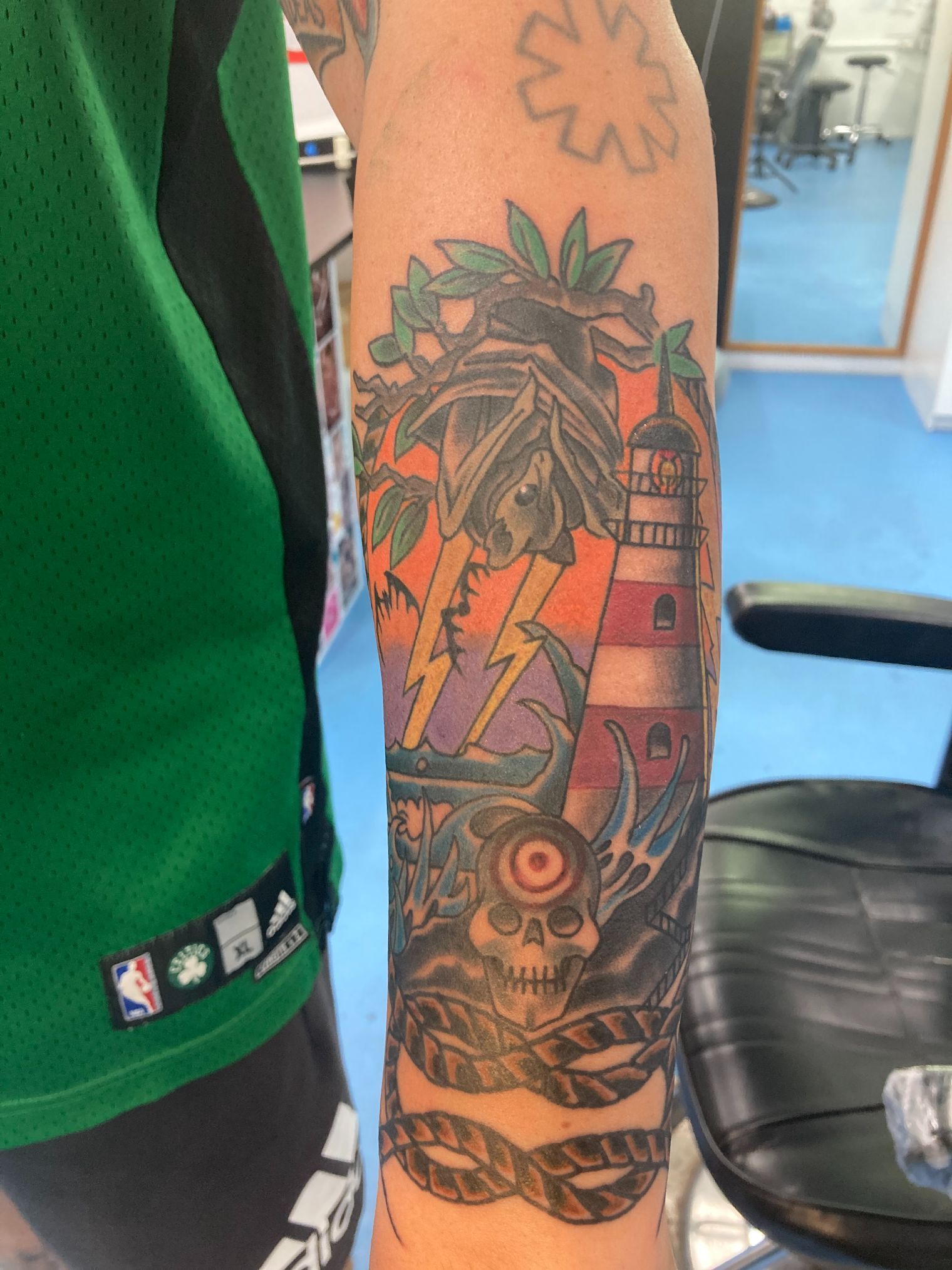 A Person Has a Tattoo of a Lighthouse and a Skull on Their Arm — La Bomba Loca Tattoo in Cairns City, QLD