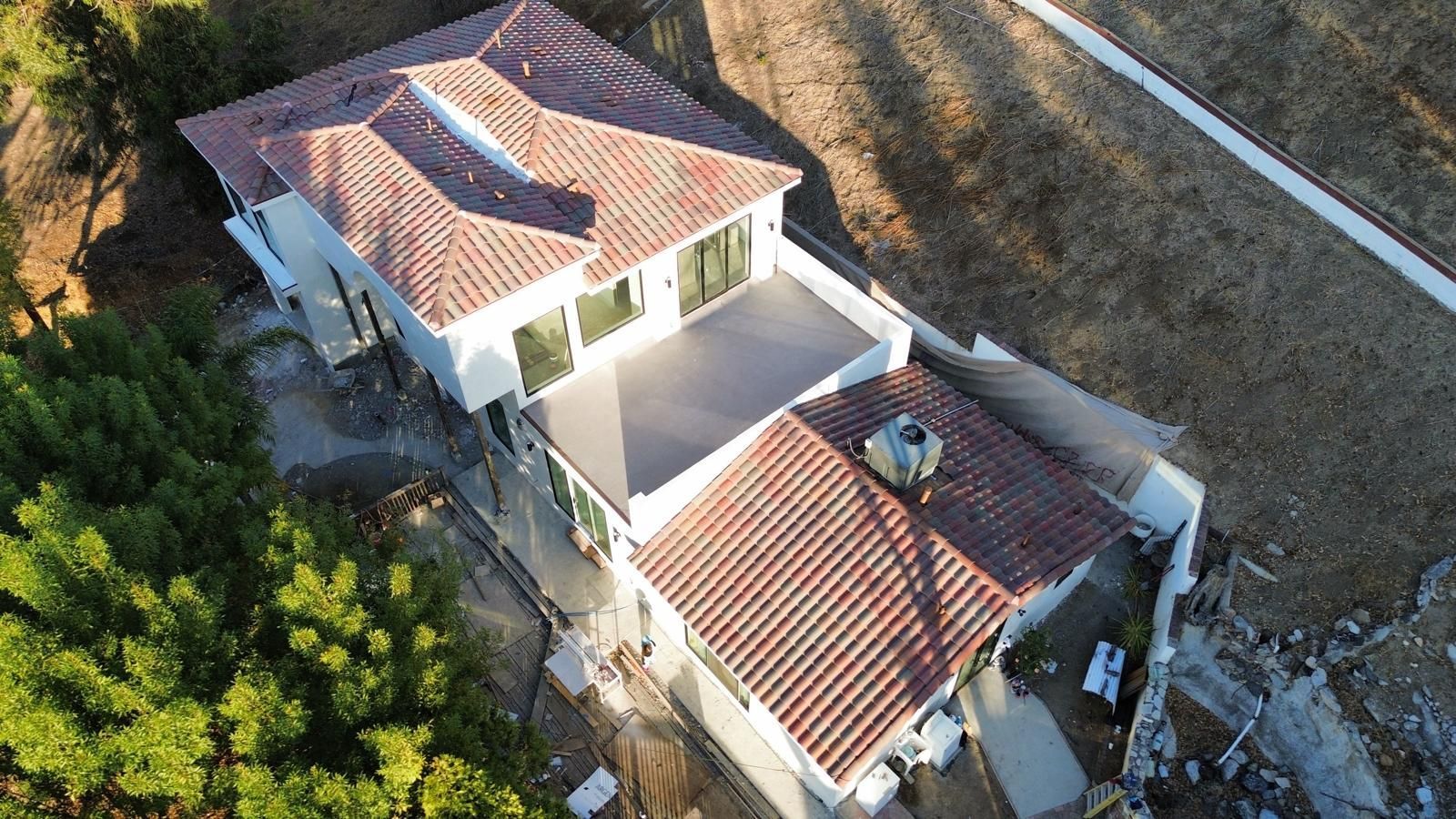 Overhead view of a two-story house with red tile roof, set on a hillside.