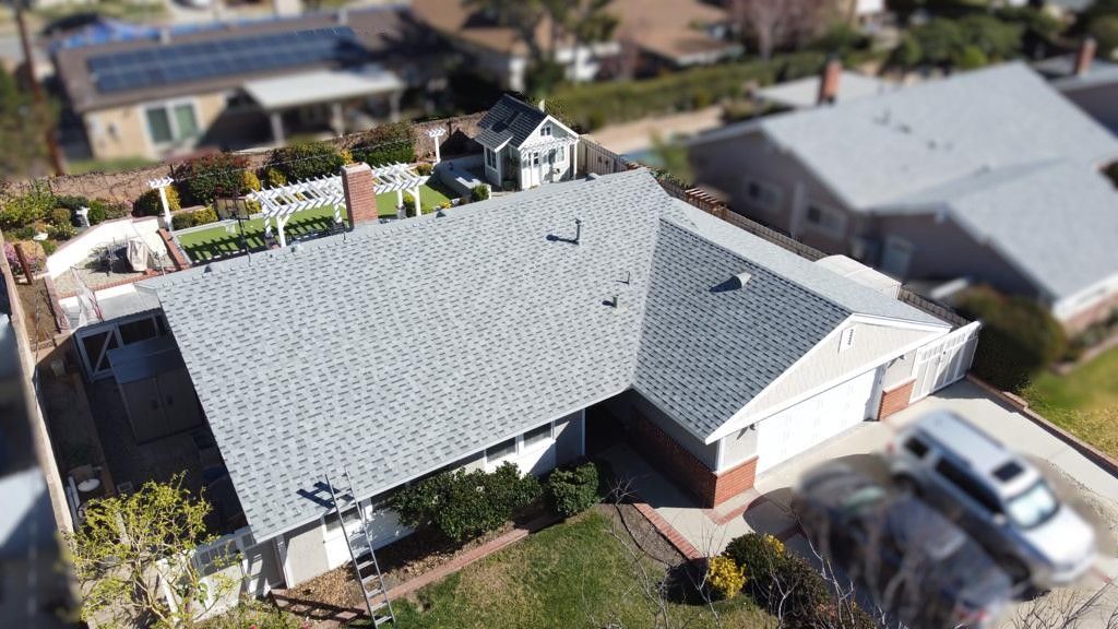 Overhead view of a house with a grey roof, white fence, and car in the driveway.
