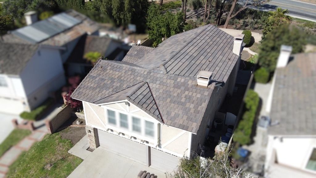 Aerial view of a house with a gray roof, beige siding, and a two-car garage.
