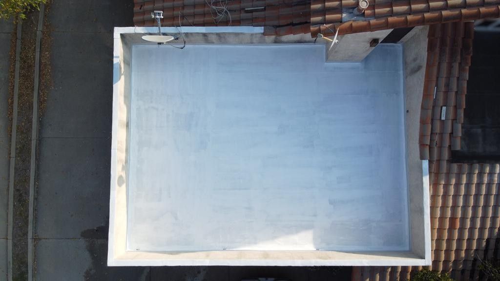 Aerial view of a light gray concrete patio surrounded by concrete walls, adjacent to a building with a tile roof.