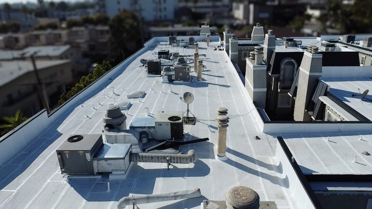 Rooftop with various mechanical equipment and chimneys, against a blurred cityscape backdrop.