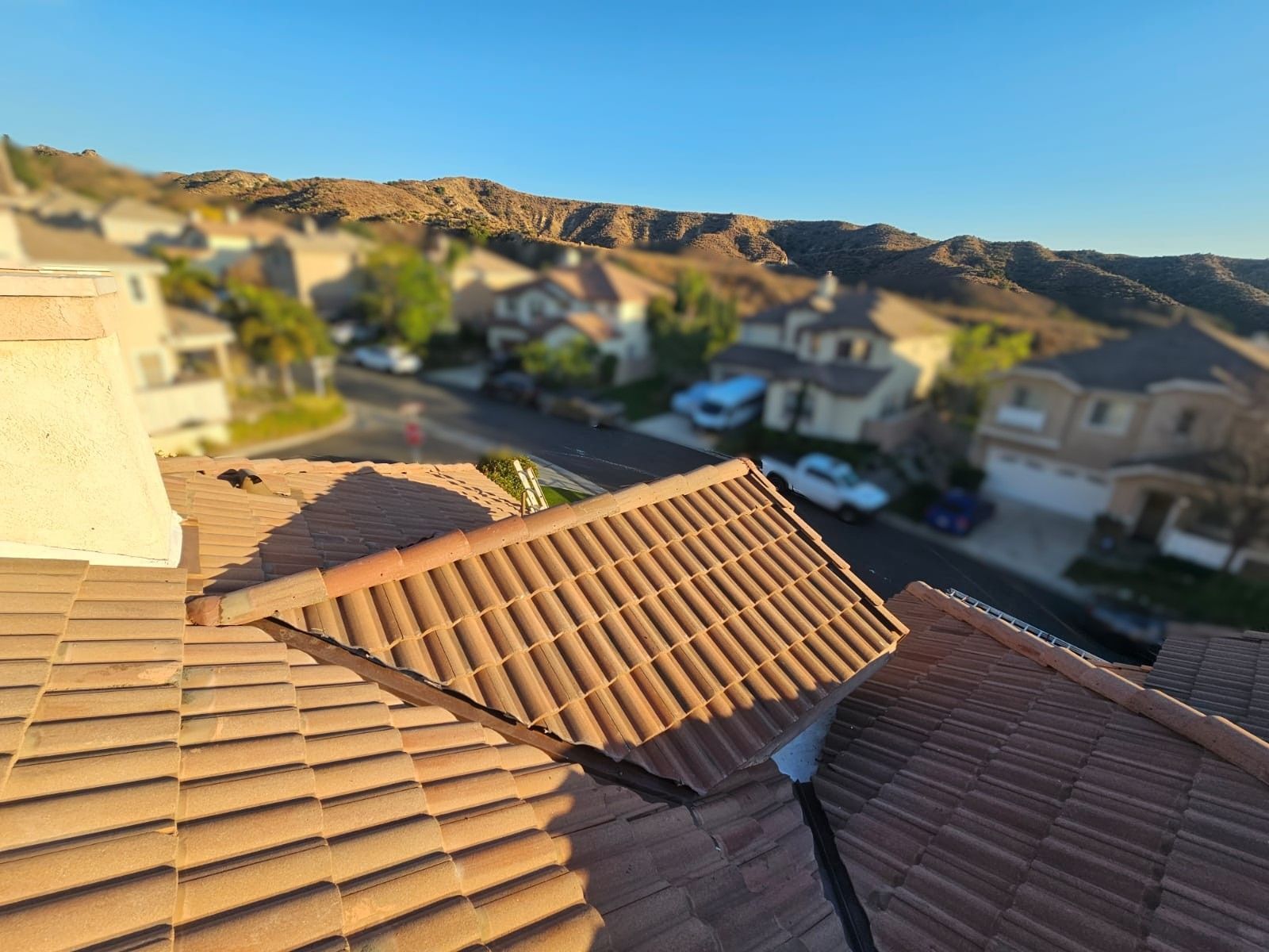 Terracotta tile roof with neighborhood and hills in background.