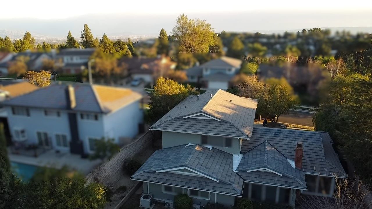 Houses nestled in a suburban neighborhood with trees, under a blue sky at sunset.