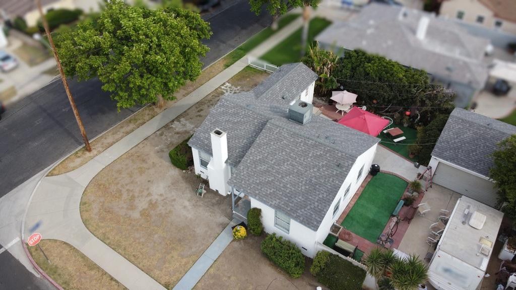 An aerial view of a white house with a gray roof, small yard, and surrounding residential area.