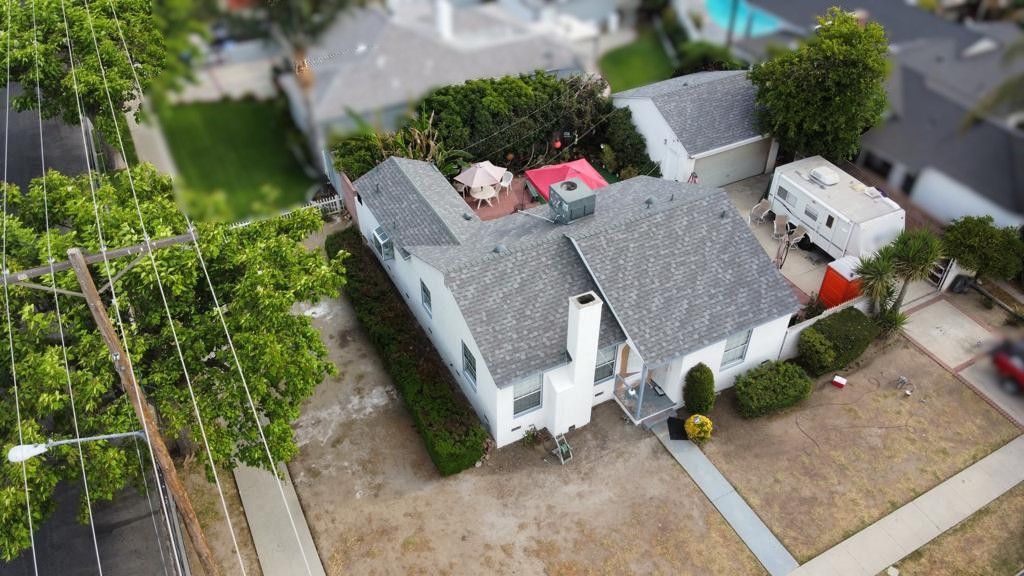 Aerial view of a white house with a grey roof and a recreational vehicle parked in the back.