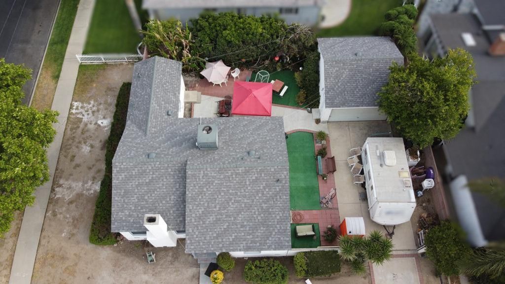Aerial view of a house with a yard, patio furniture, RV, and green and red accents.