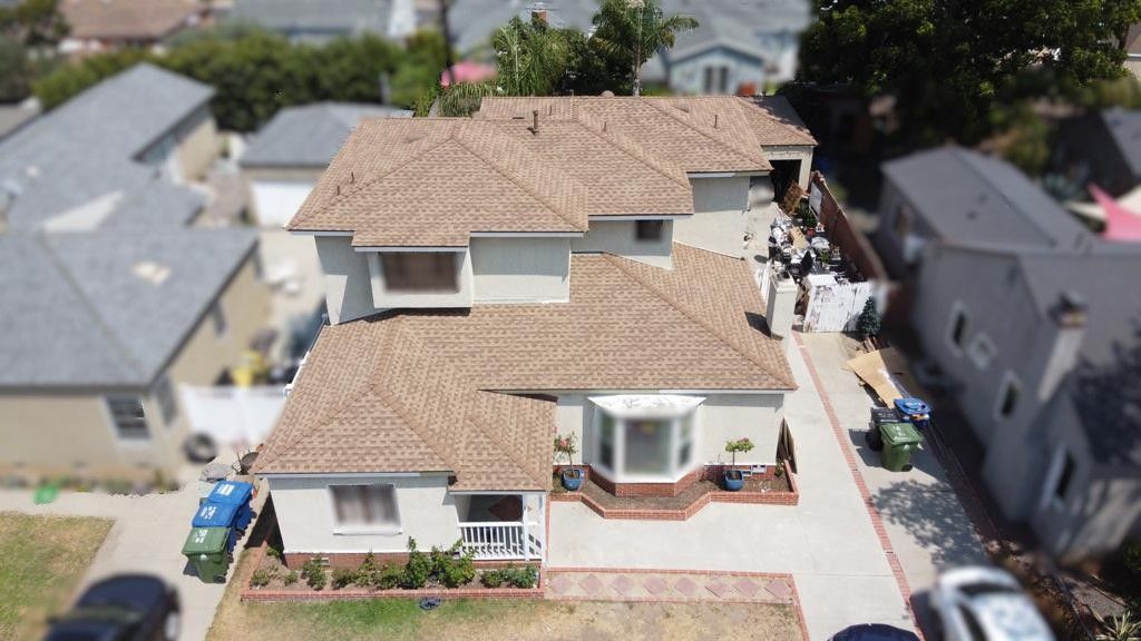 Aerial view of a two-story house with brown tile roof and a driveway, in a residential neighborhood.