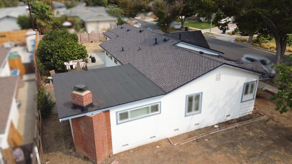 White house with black roof, red brick chimney. Sunny outdoor setting.