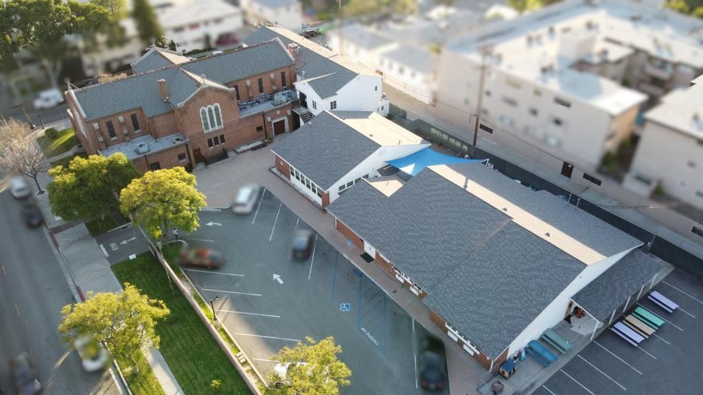 Aerial view of a brick church building with a parking lot and adjacent smaller building.