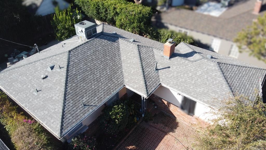 Overhead view of a house with a grey roof, surrounded by greenery.