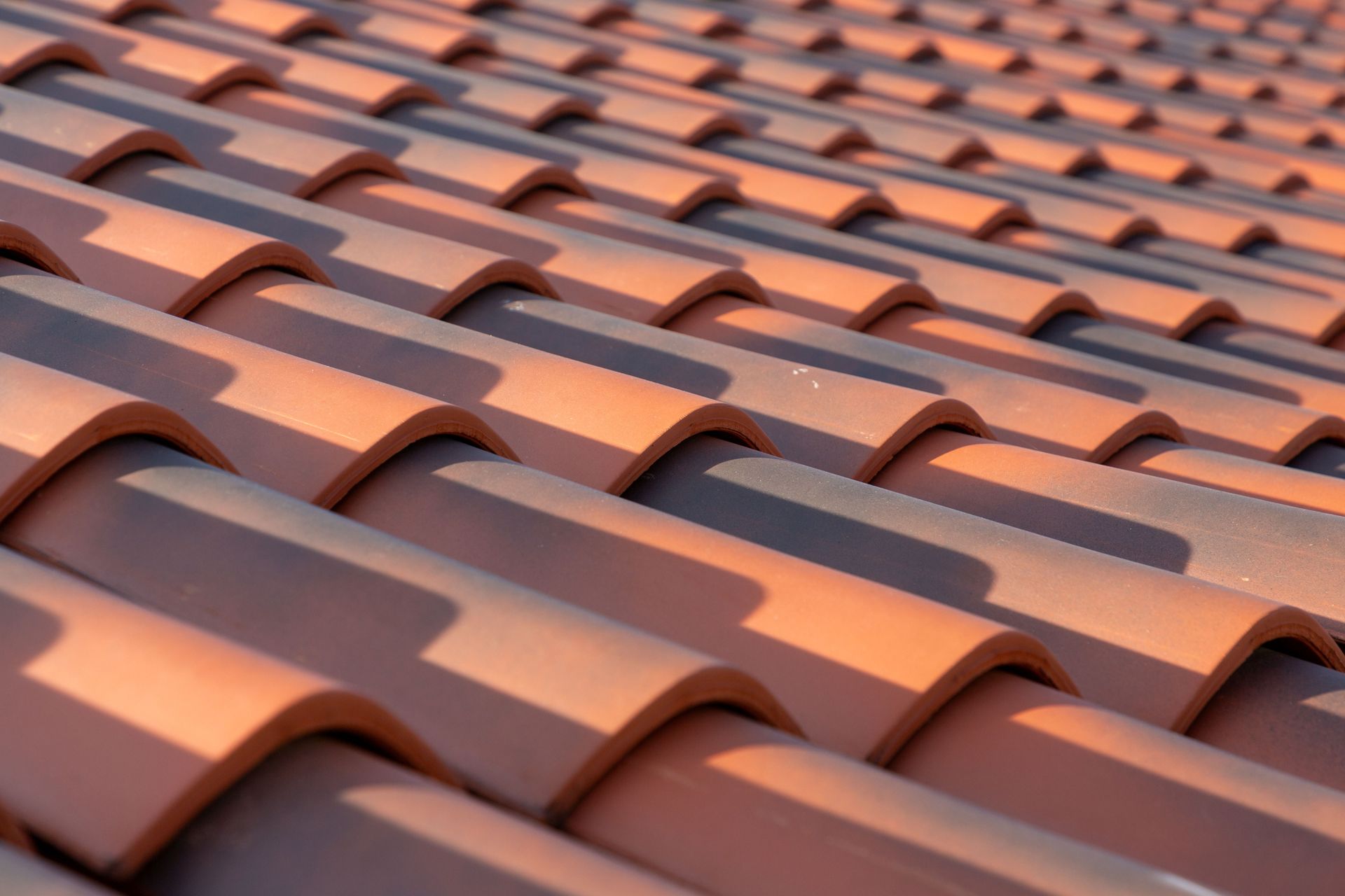 Red clay roof tiles, close-up view showing rows and shadows.