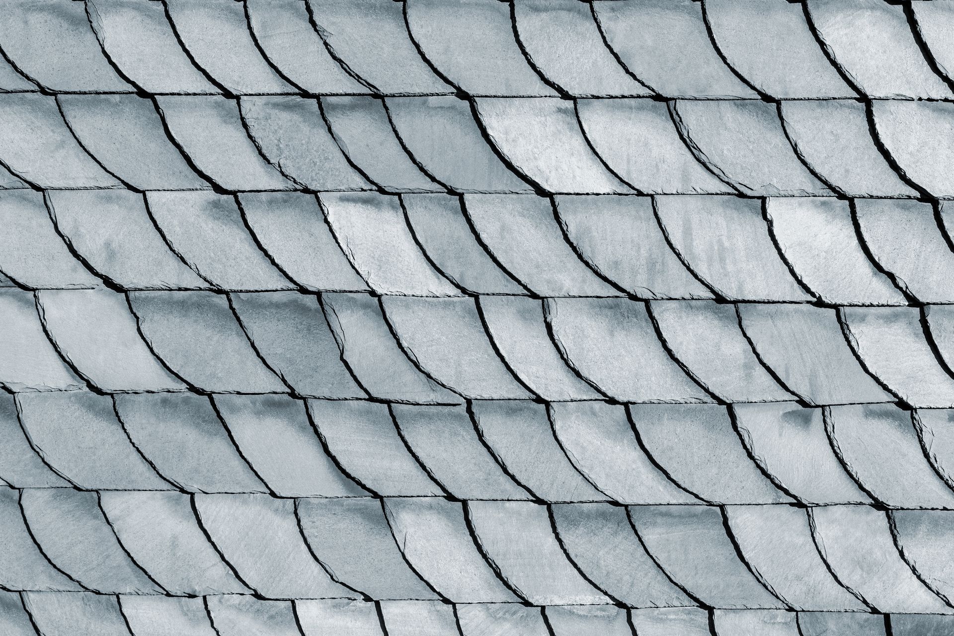 Gray, scalloped roof tiles arranged in overlapping rows.