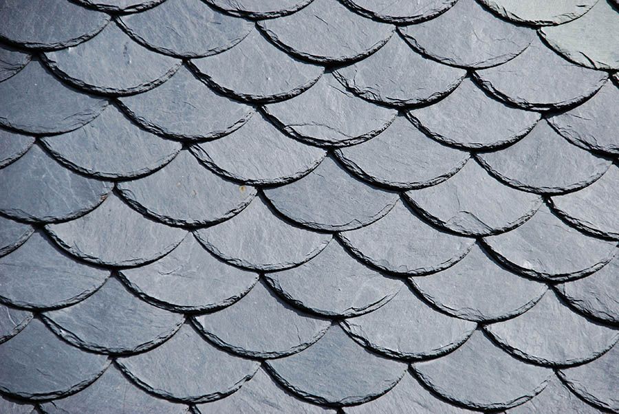 Gray, scale-shaped roof tiles arranged in overlapping rows, creating a textured pattern.