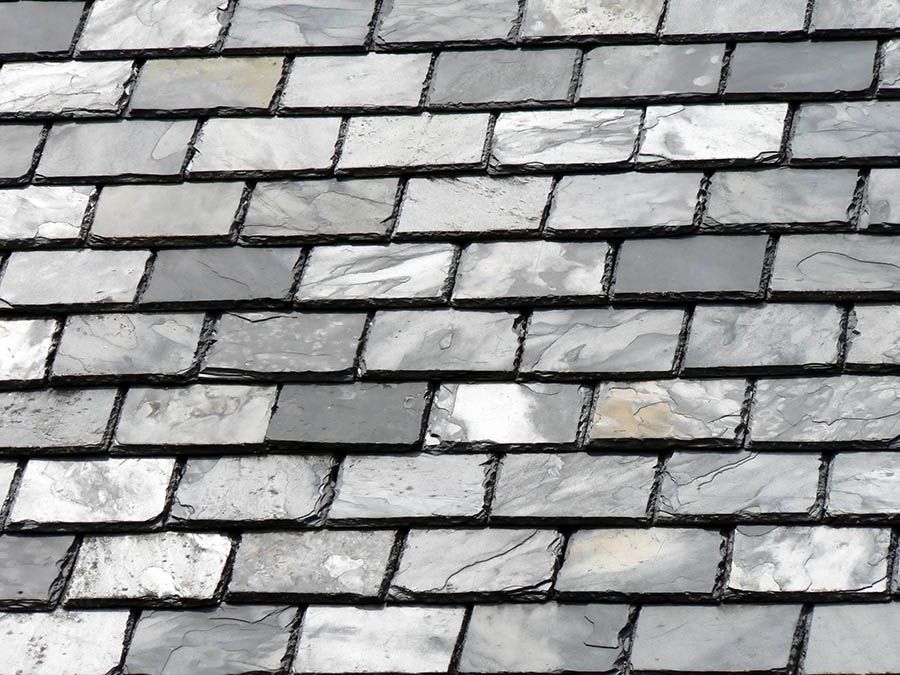 Close-up of a gray slate roof, tiles overlapping in a traditional pattern, varying shades.