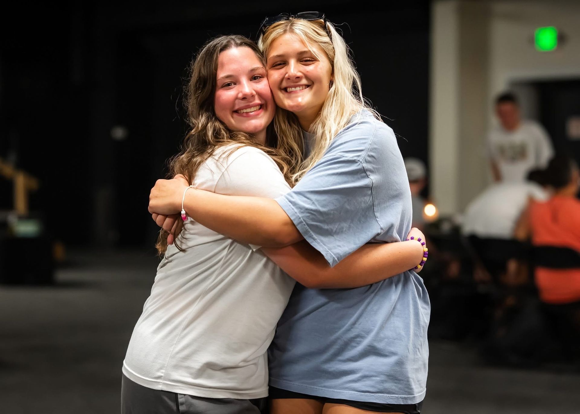 Two young people embracing and smiling. Dim interior setting.