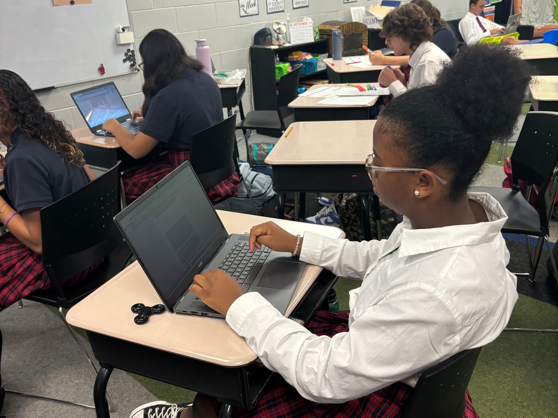 Students in a classroom working on laptops at individual desks.