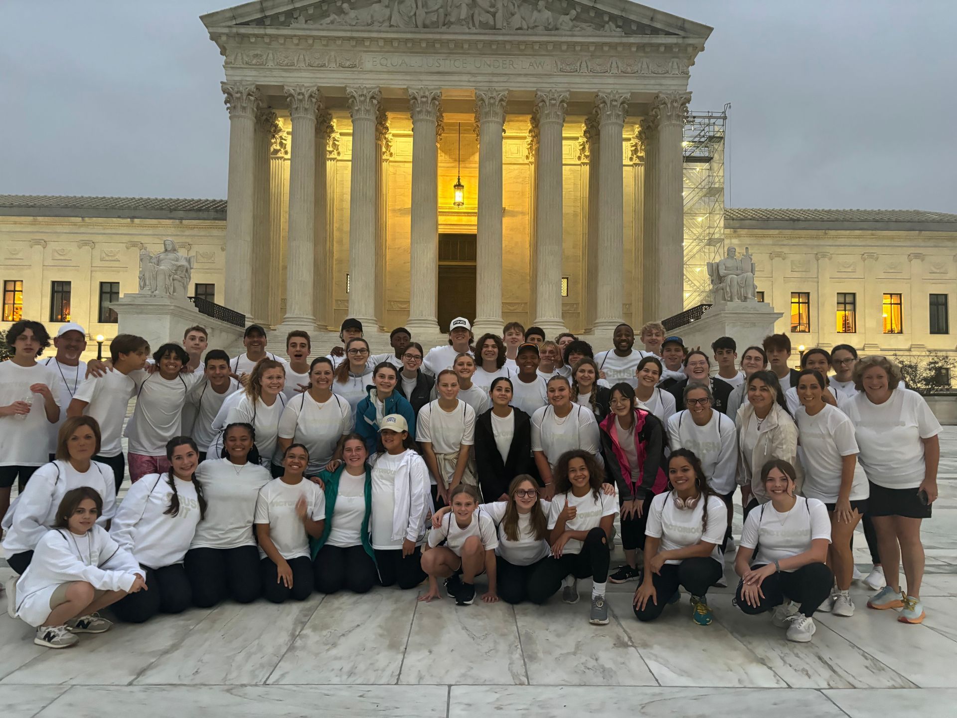 Group of people in white clothing in front of the Supreme Court building.