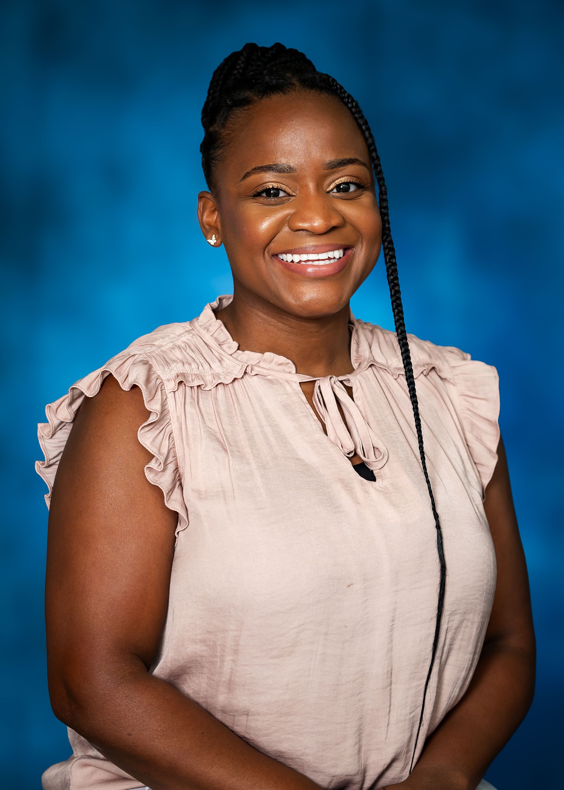 Woman smiling, wearing a pink blouse, against a blue background.
