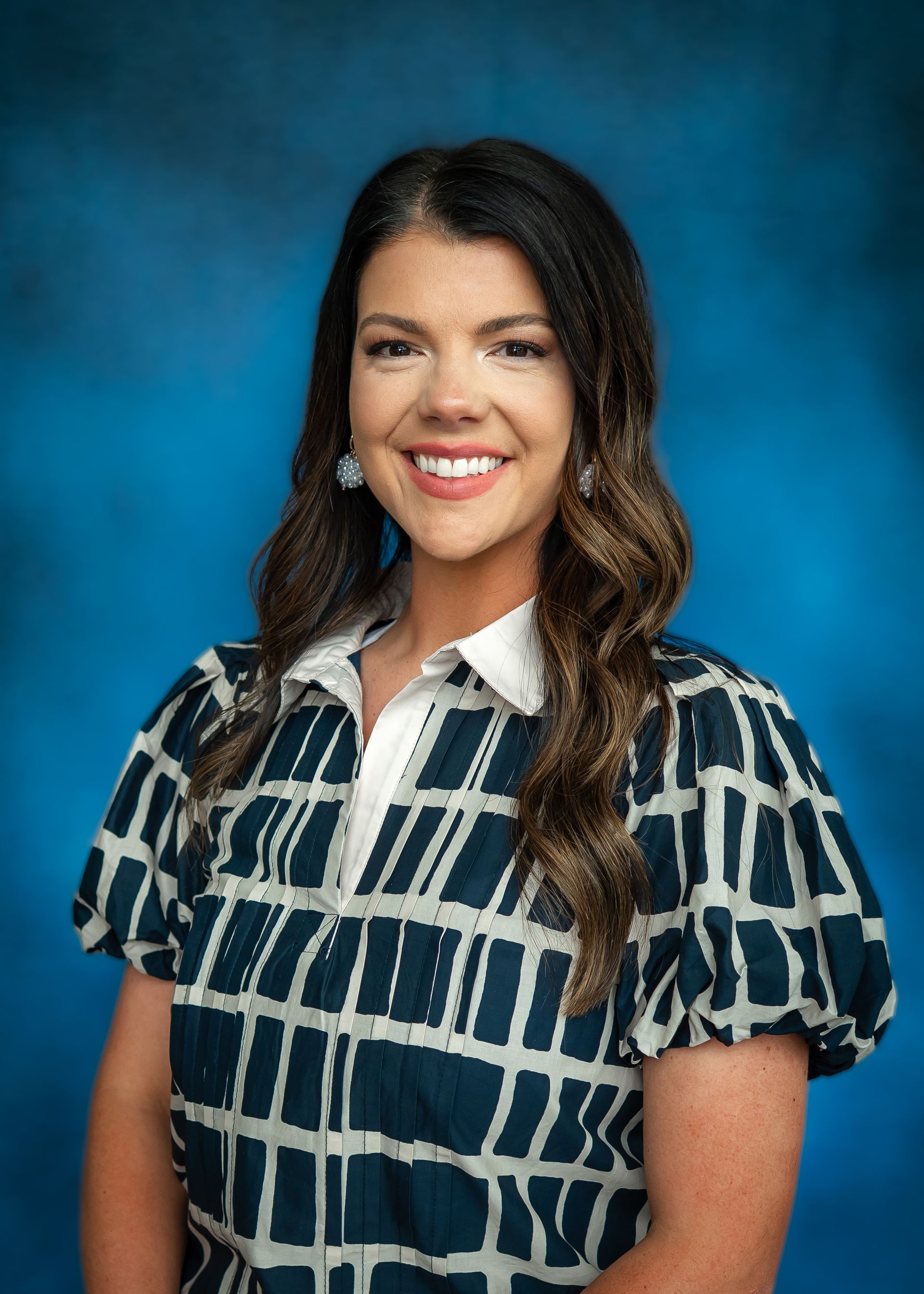 Woman with long brown hair, blue and white square print blouse, blue background.