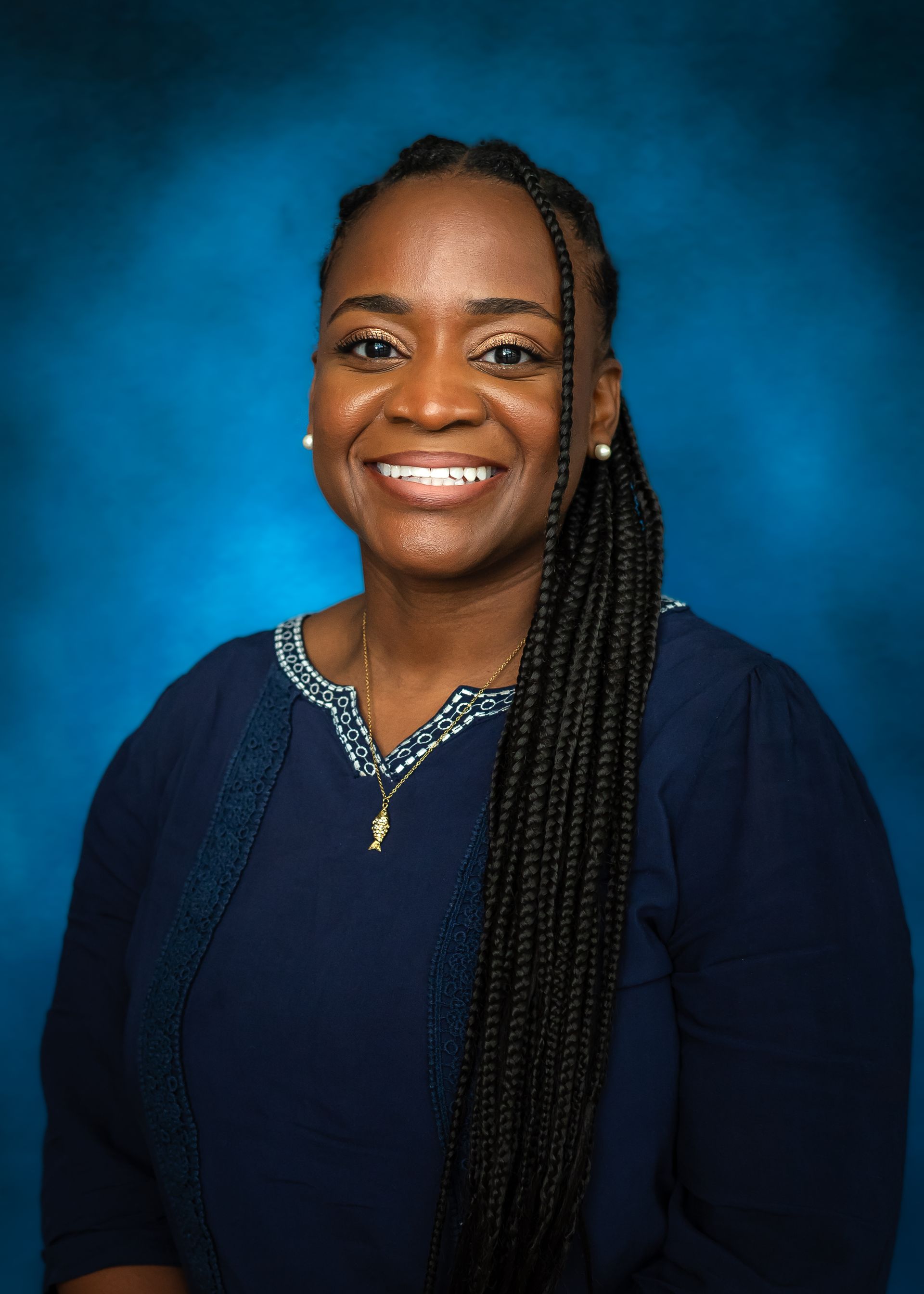 Woman smiling, wearing a navy blouse, against a blue background.