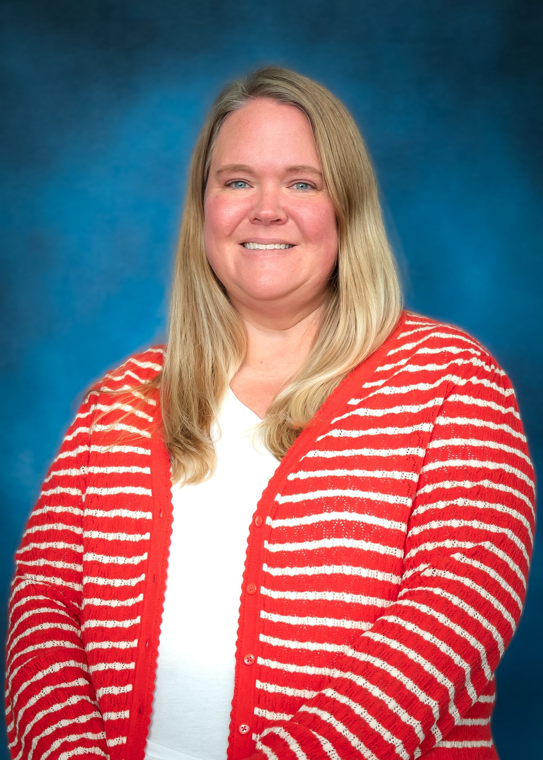 Woman with long blonde hair, smiling, wearing a red and white striped shirt, against a blue background.