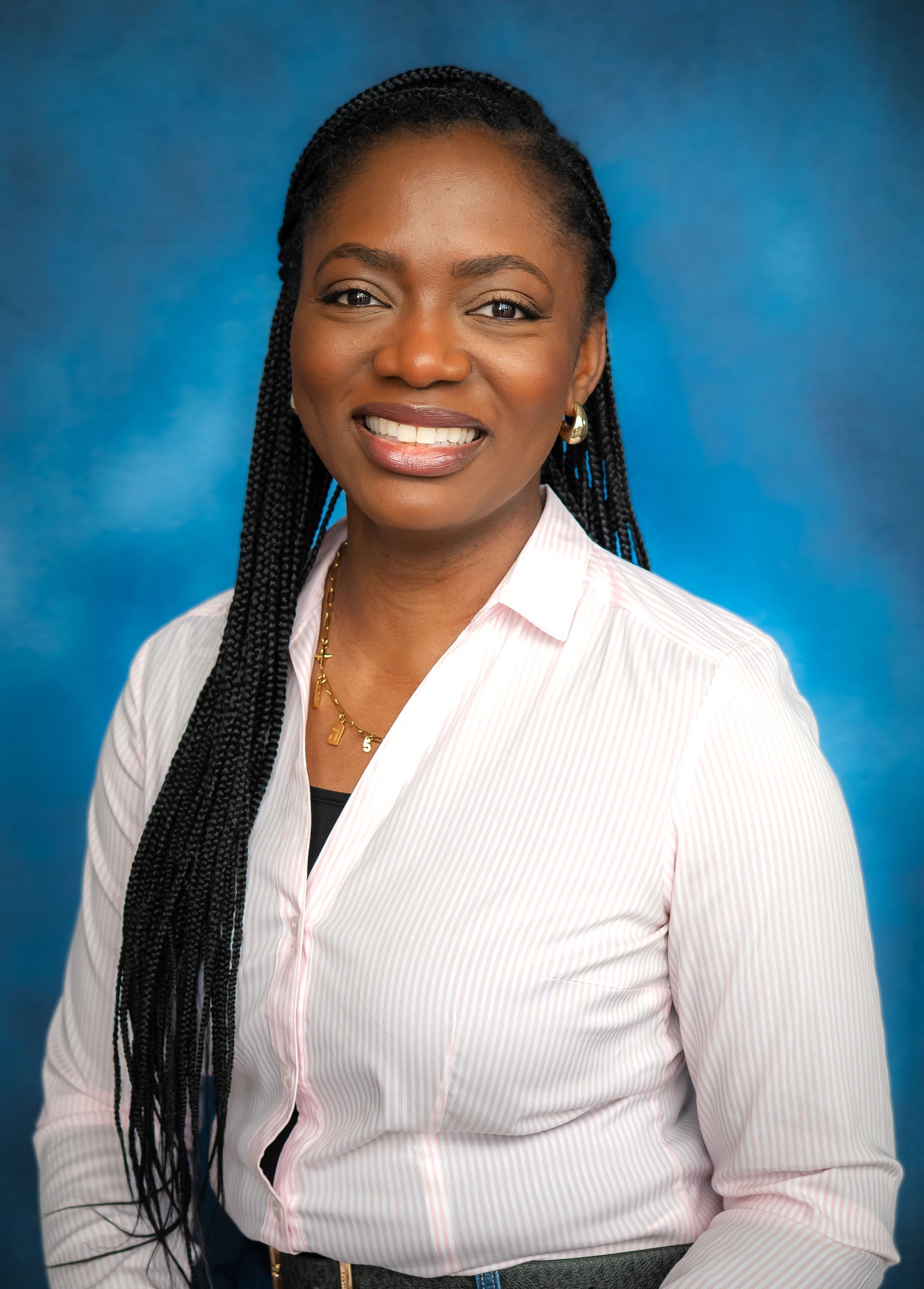 Woman wearing white shirt, smiling, with long braids against blue background.