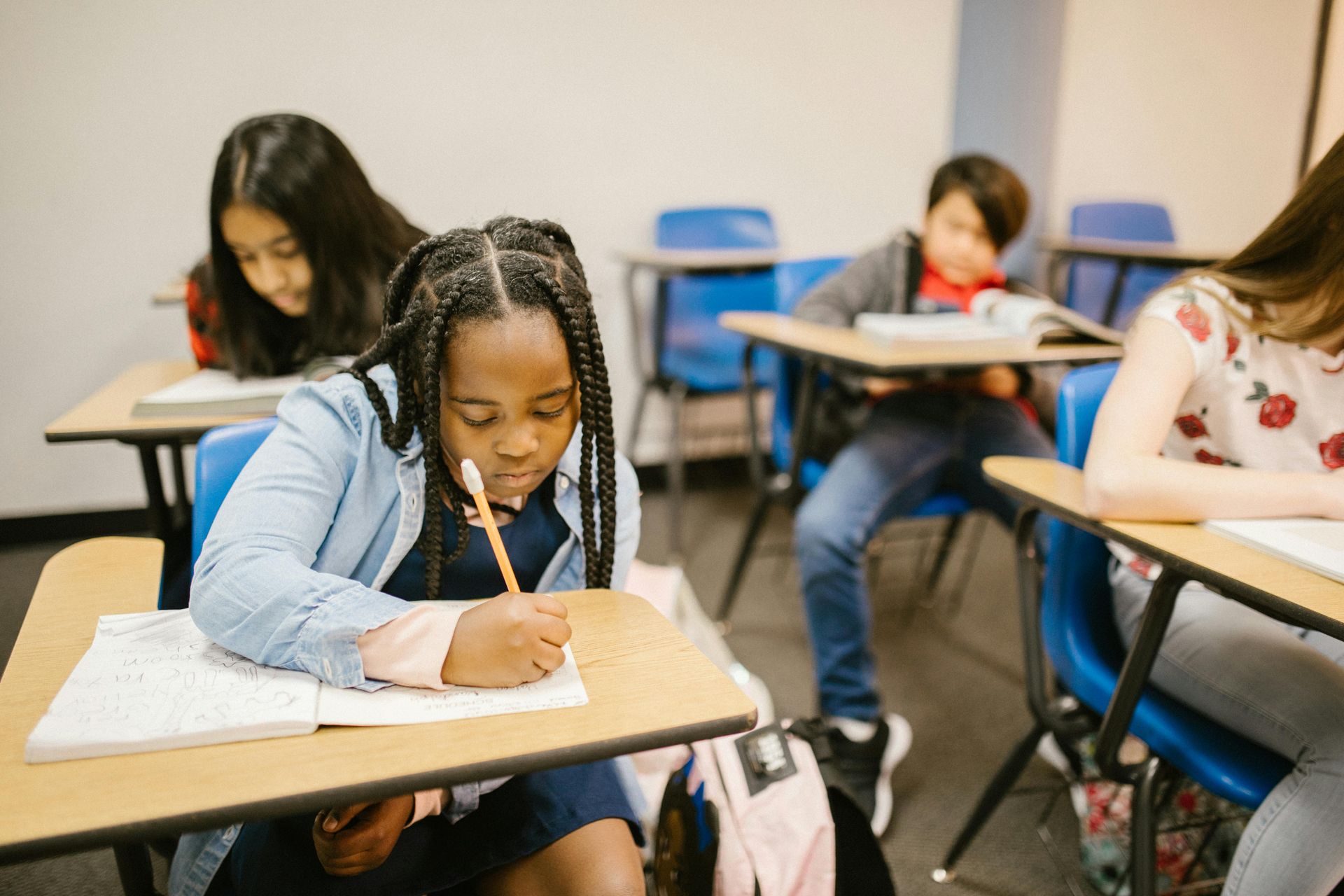 Students writing at desks in a classroom.
