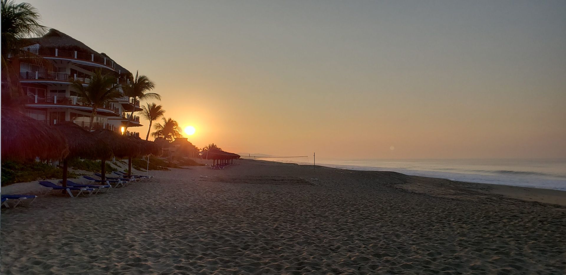 Bedroom with bed, side tables, ocean view, and wood paneling.