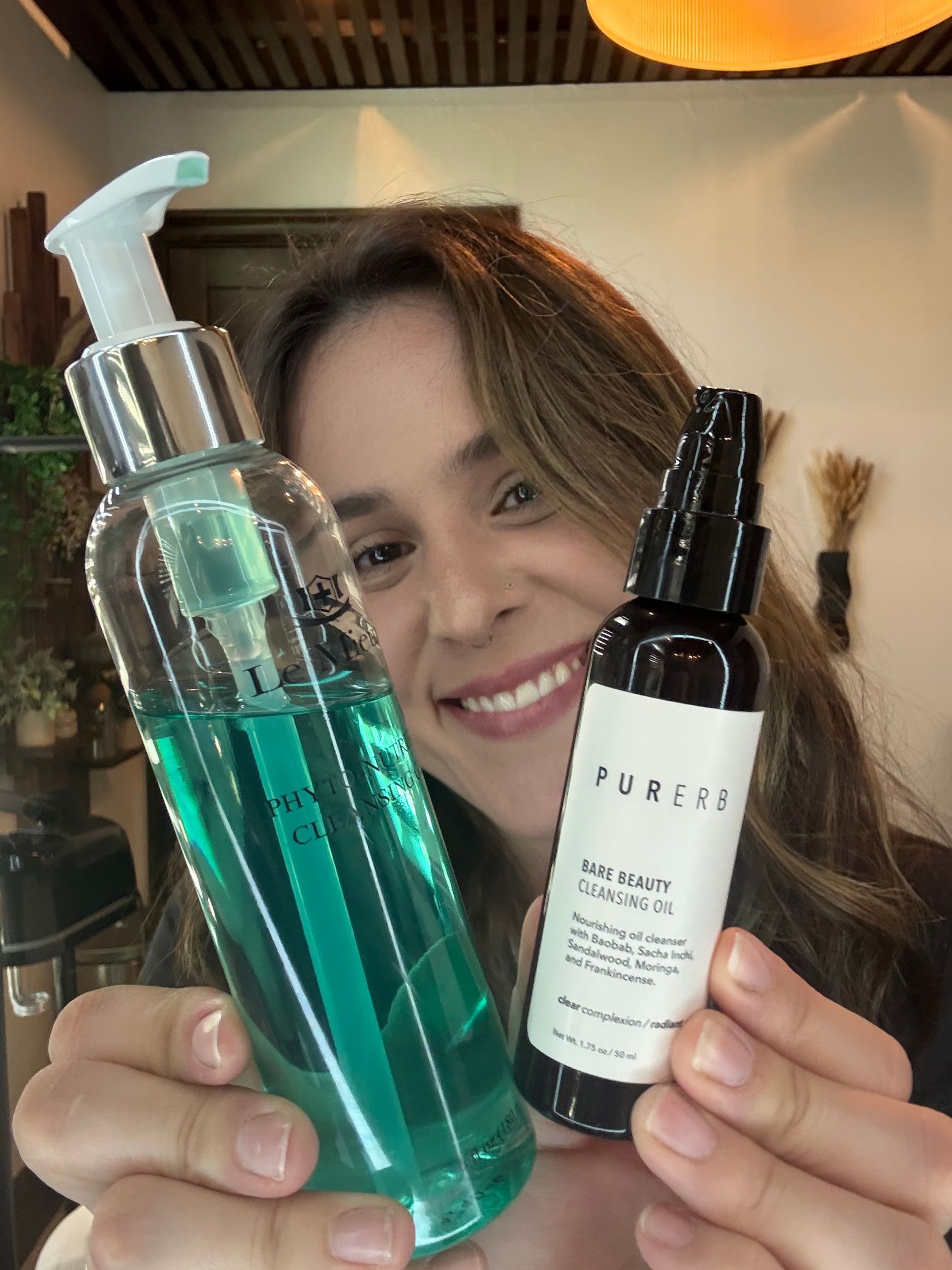 A woman is holding a spray bottle and a bottle of liquid