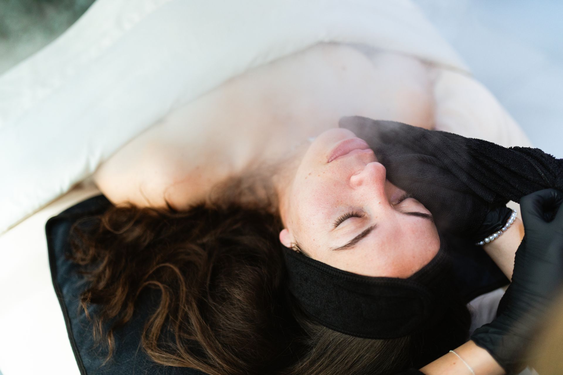 A woman is laying on a bed with a mask on her face.