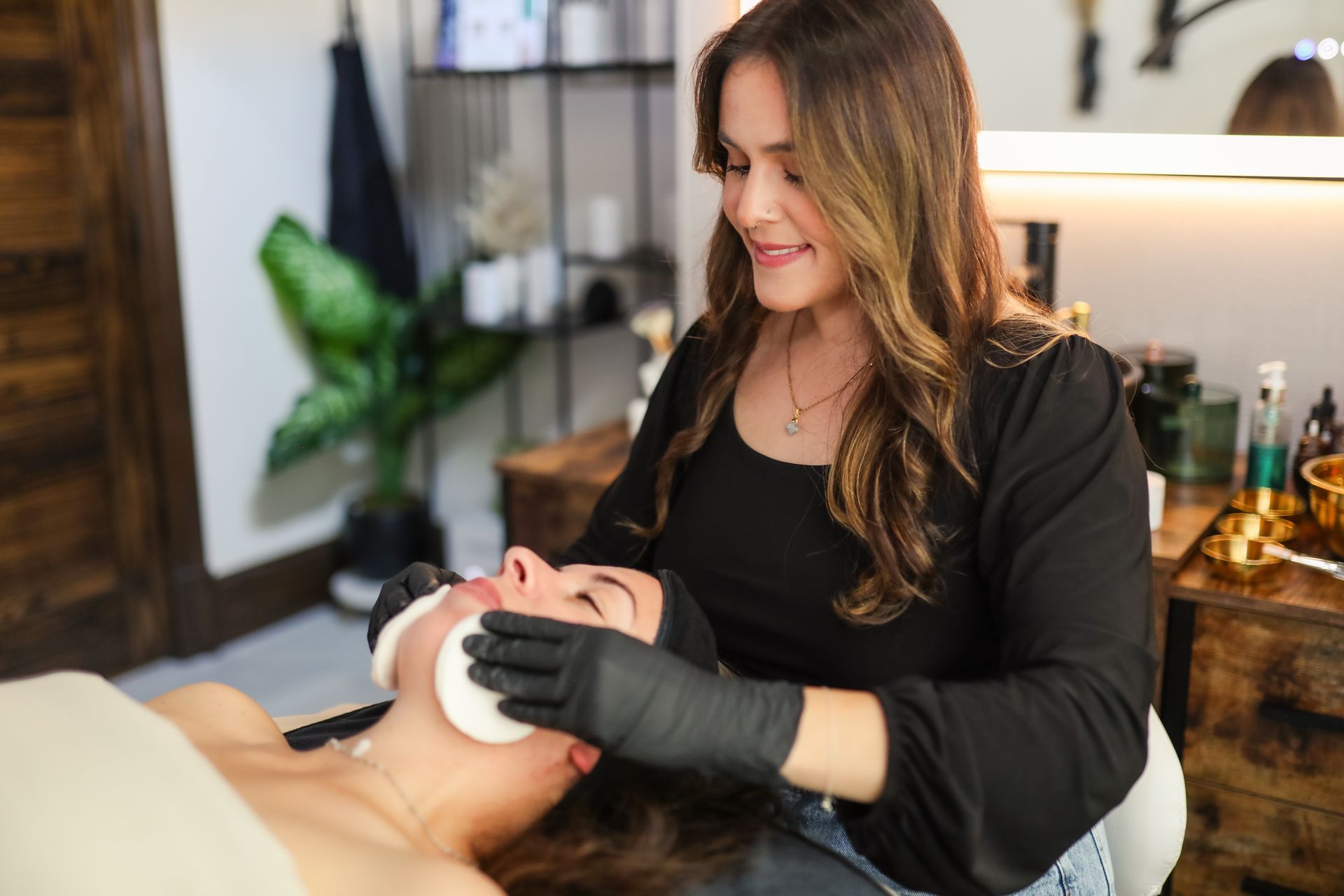 A woman is cleaning a woman 's face with a sponge in a beauty salon.