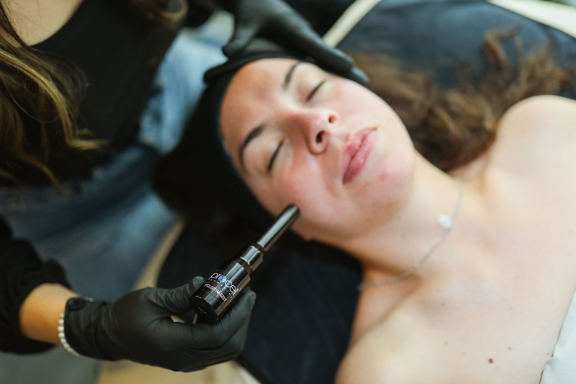 A woman is laying on a bed getting a facial treatment.