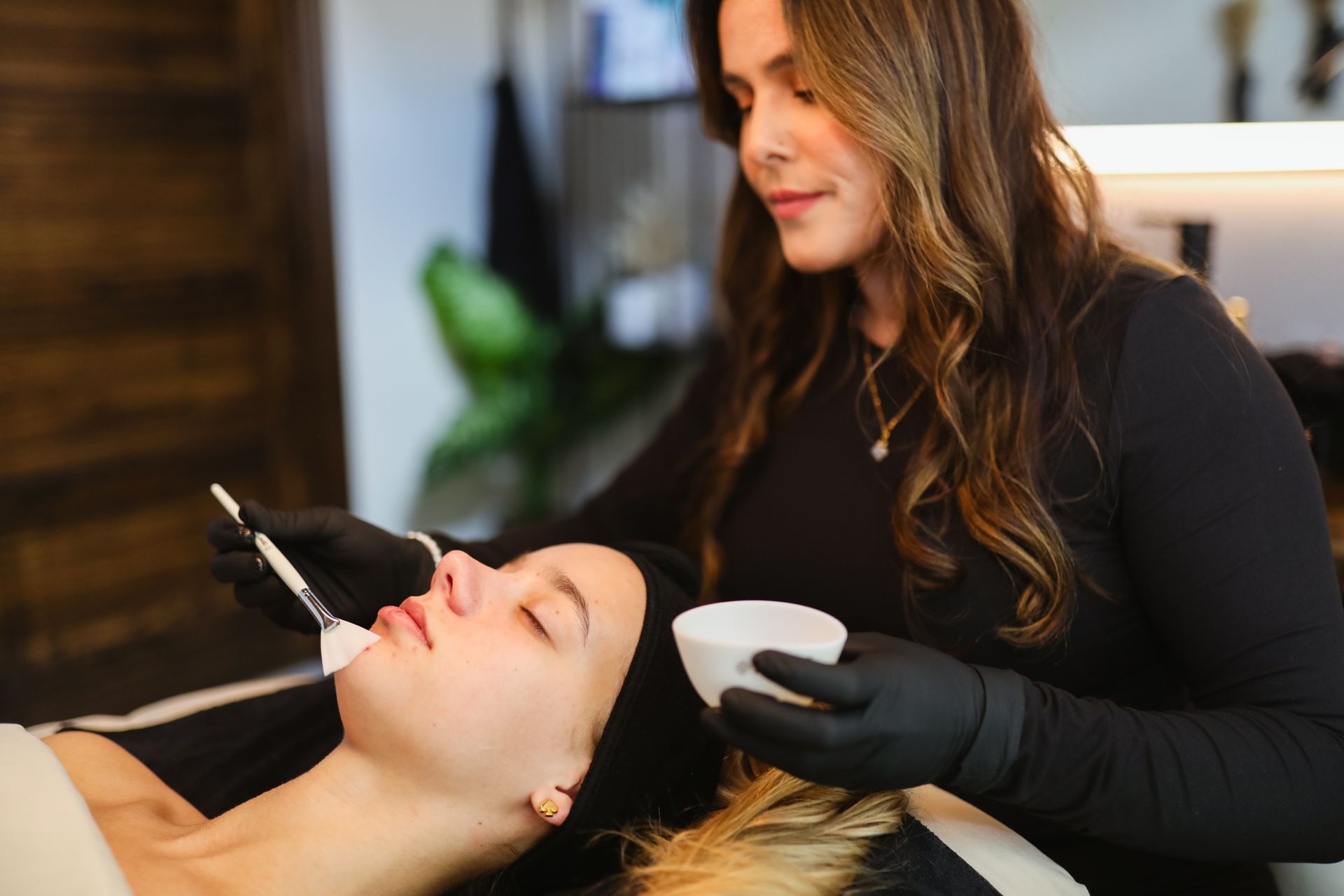 A woman is applying a facial treatment to a woman 's face.