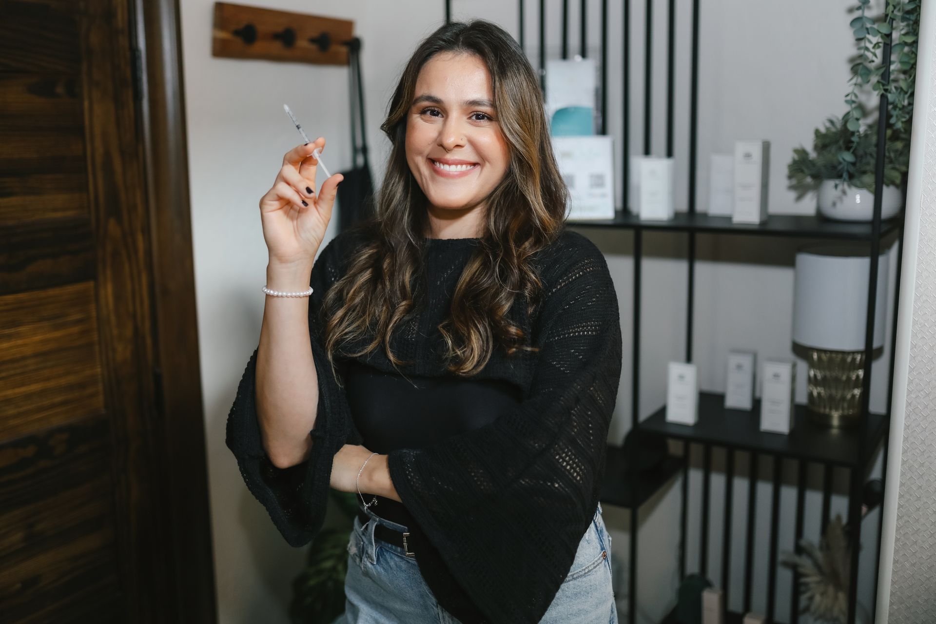 A woman is standing in a room holding a bottle and smiling.