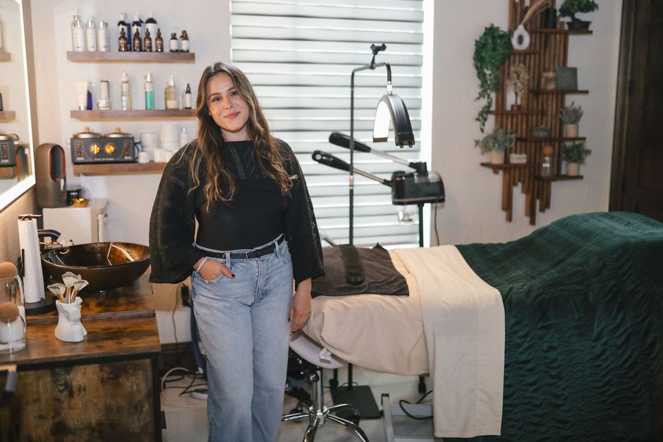 A woman is standing in a salon next to a bed.