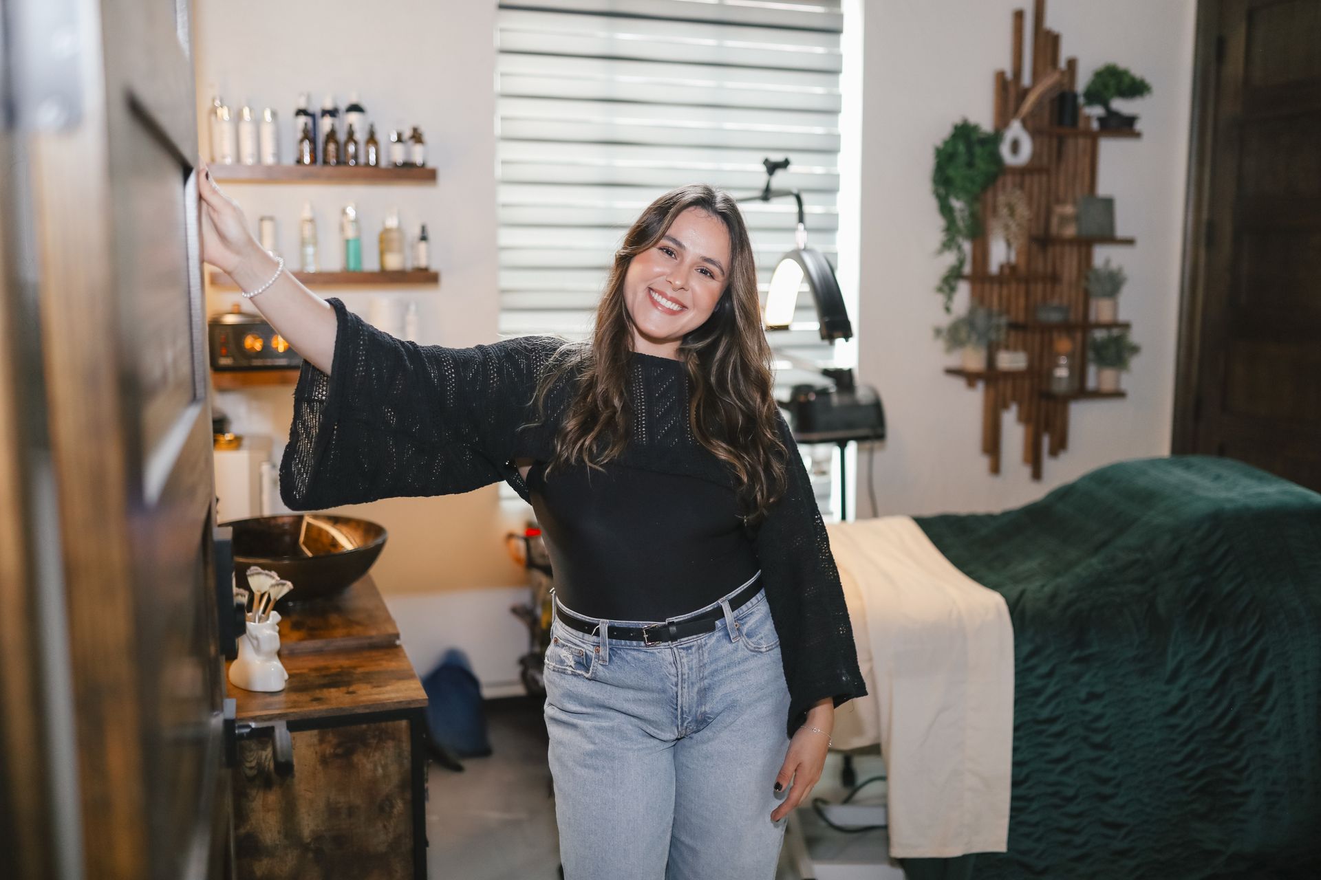 A woman is standing in a salon next to a bed.