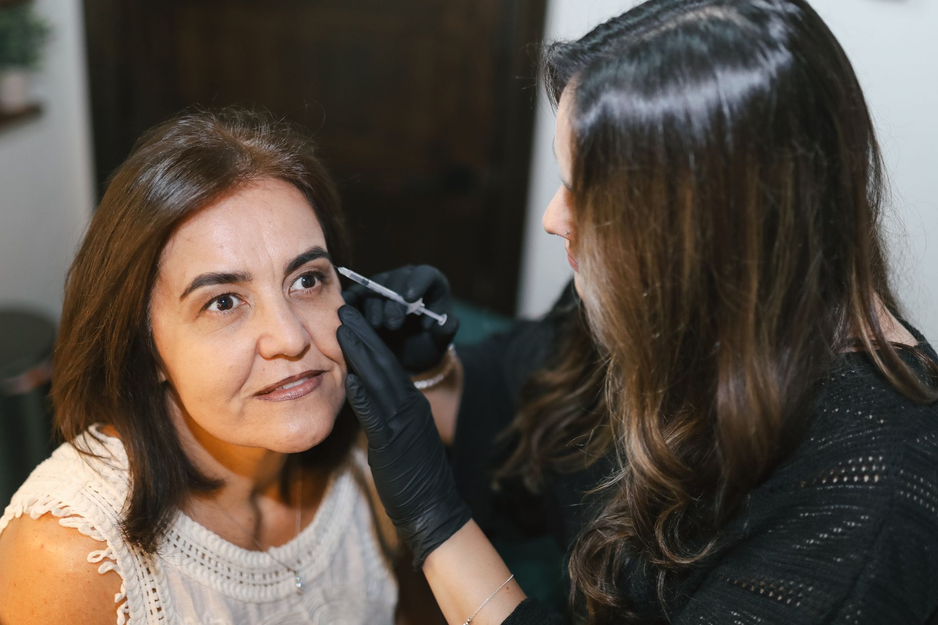 A woman is getting her eyebrows done by a makeup artist.