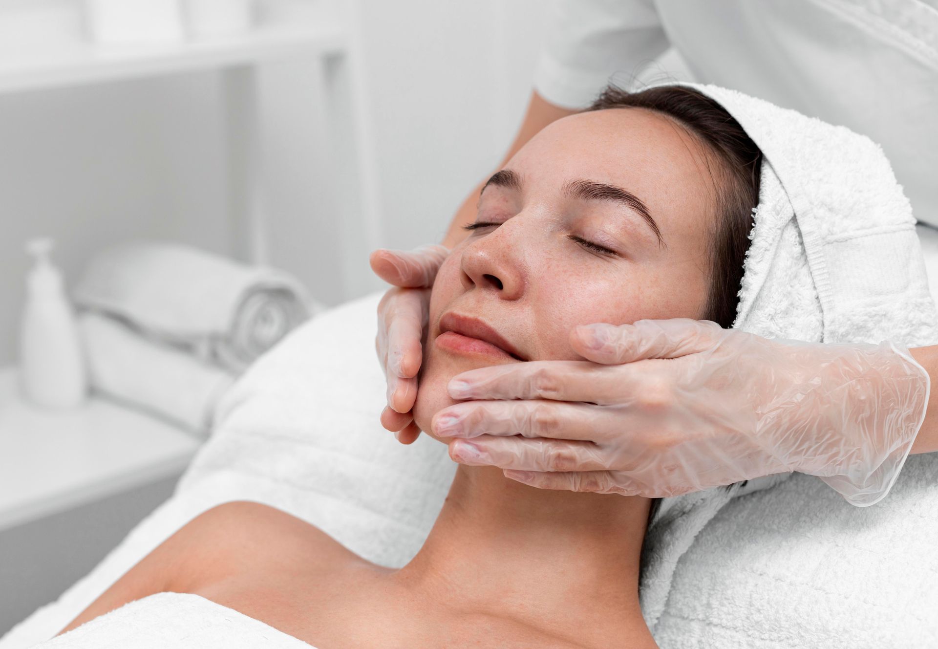 A woman is getting a facial massage at a spa.