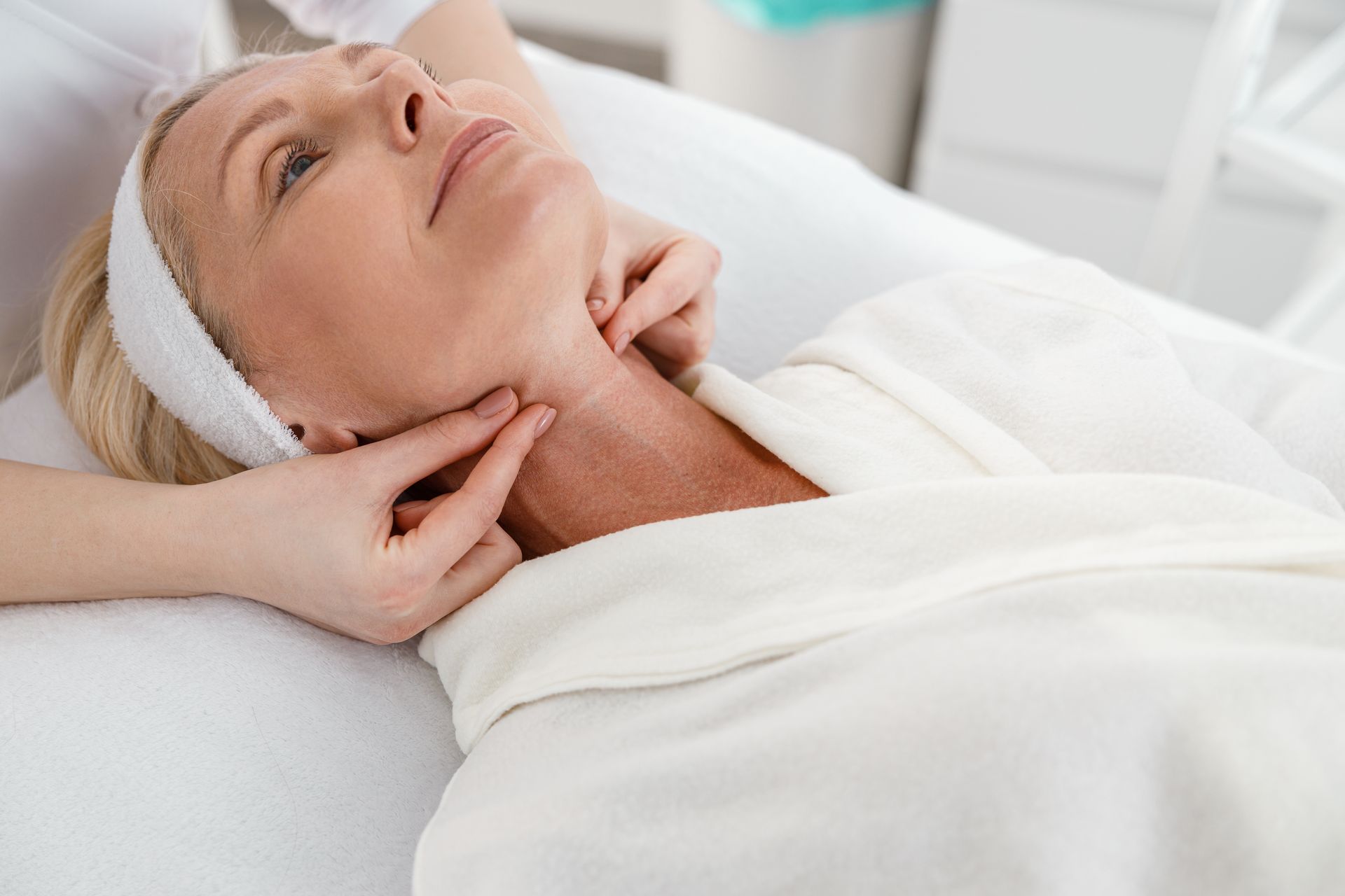 A woman is getting a massage on her neck in a spa.