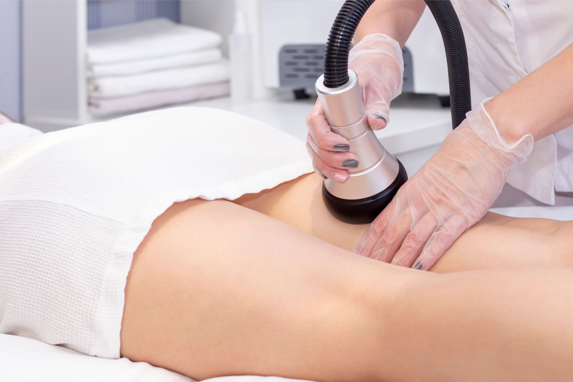 A woman is getting a cavitation treatment on her legs.