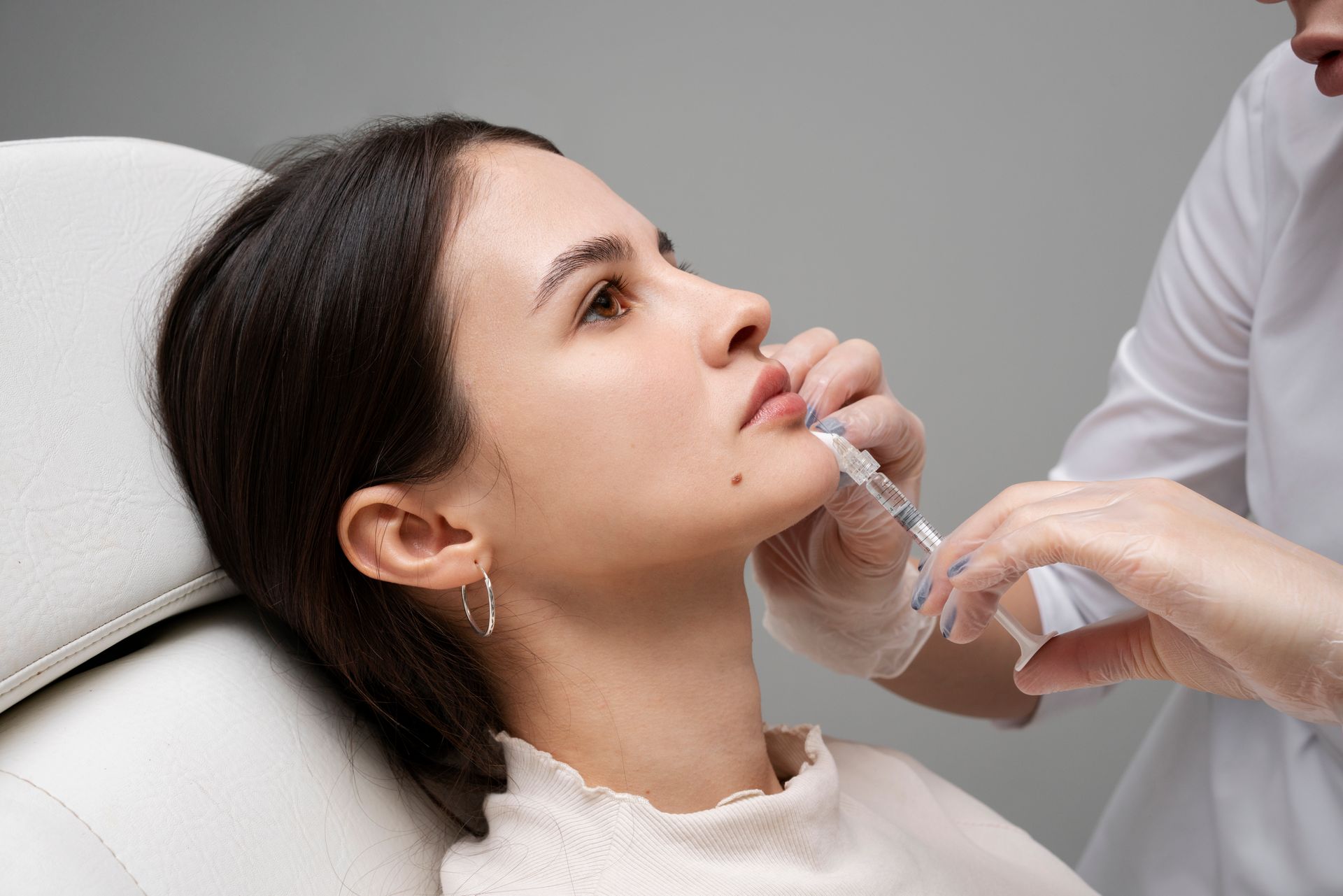 Patient receiving a facial injection from a clinician in a treatment room