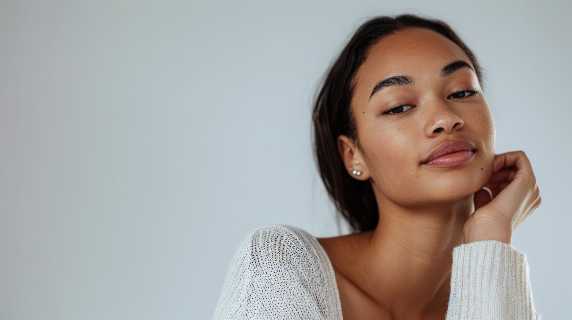 A close up of a woman wearing a white sweater and earrings.