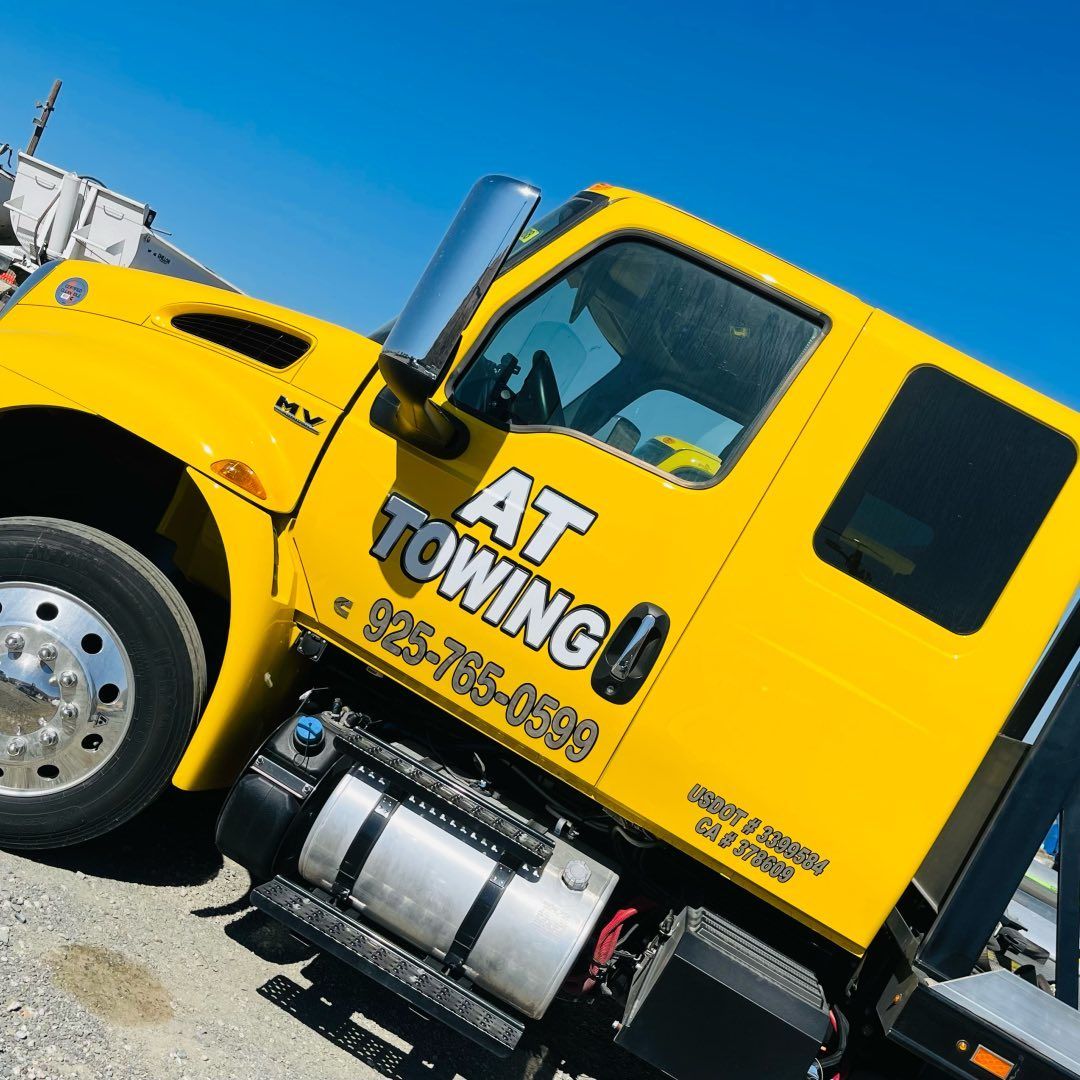 A yellow towing truck is parked on the side of the road