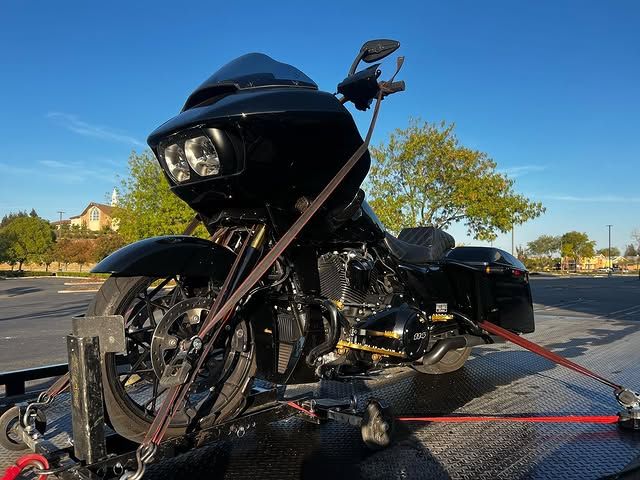 A black harley davidson motorcycle is being towed by a red strap.