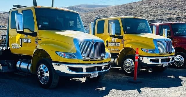Two yellow trucks are parked next to each other in a parking lot.