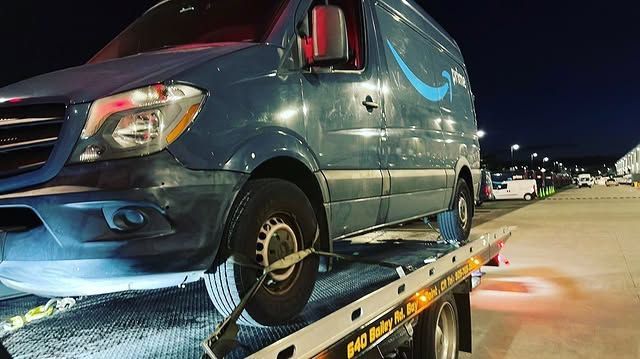 A blue van is sitting on top of a tow truck.