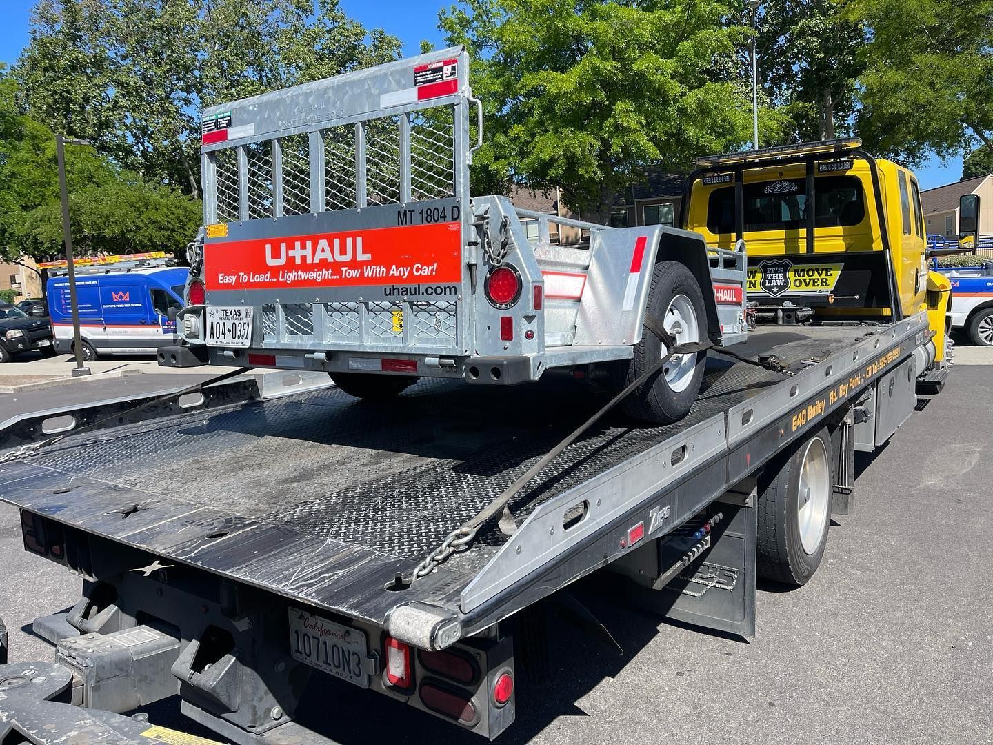 A uhaul trailer is being towed by a tow truck
