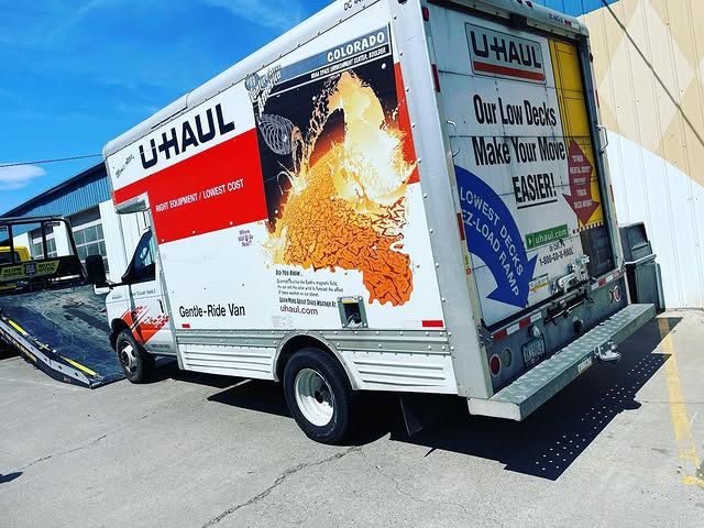 A u-haul truck is parked in front of a building.