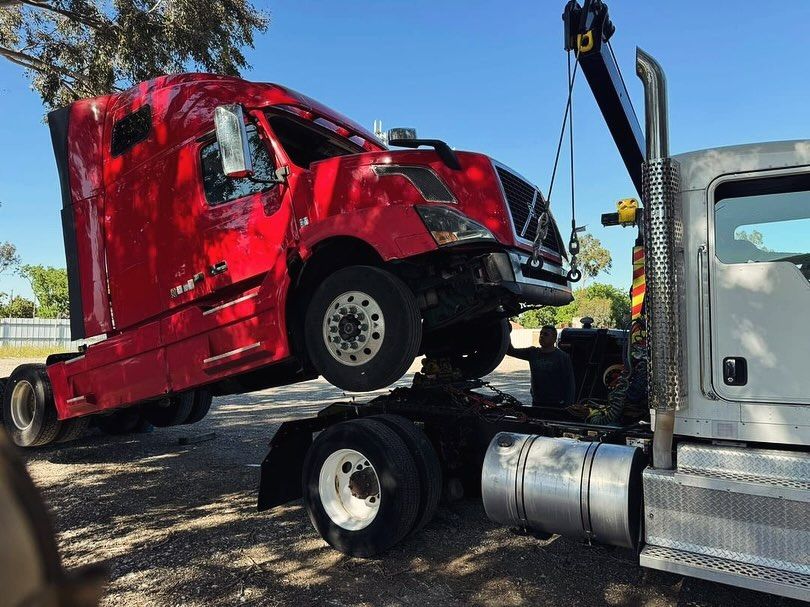A red semi truck is being towed by a tow truck